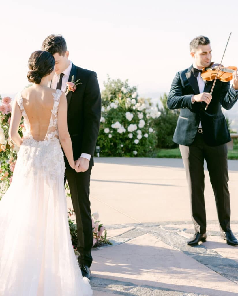 Mand, der spiller violin foran et brudepar.
