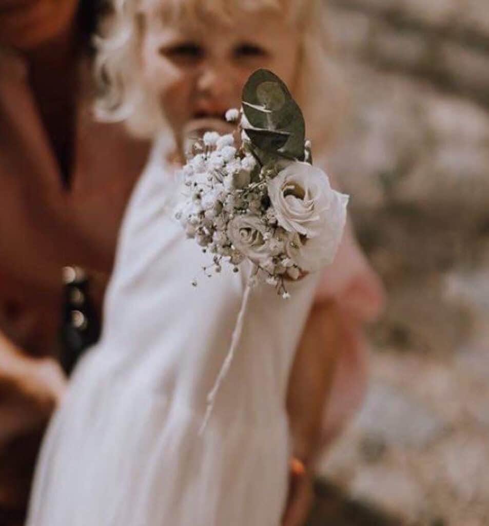 En glad lille pige står med en smuk buket blomster i hænderne.