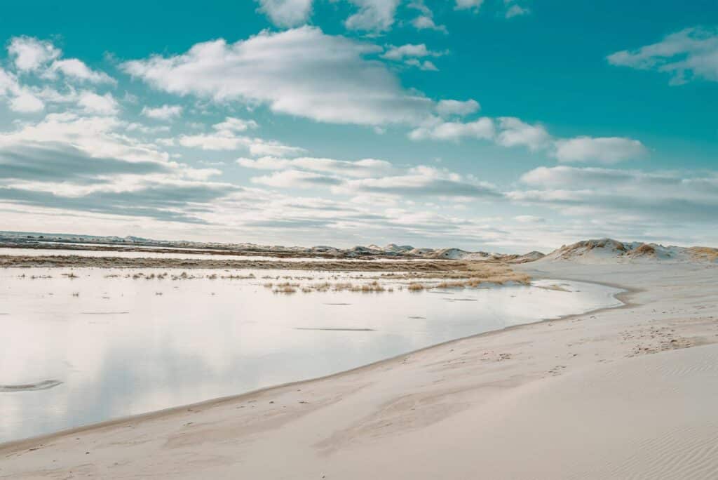 Sandstrand ved Skagen med bølger og skyer, der skaber en rolig og naturskøn atmosfære.