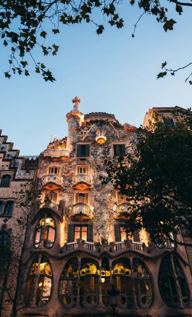 Casa Batlo i Barcelona med mange vinduer og frodige træer omkring bygningen.
