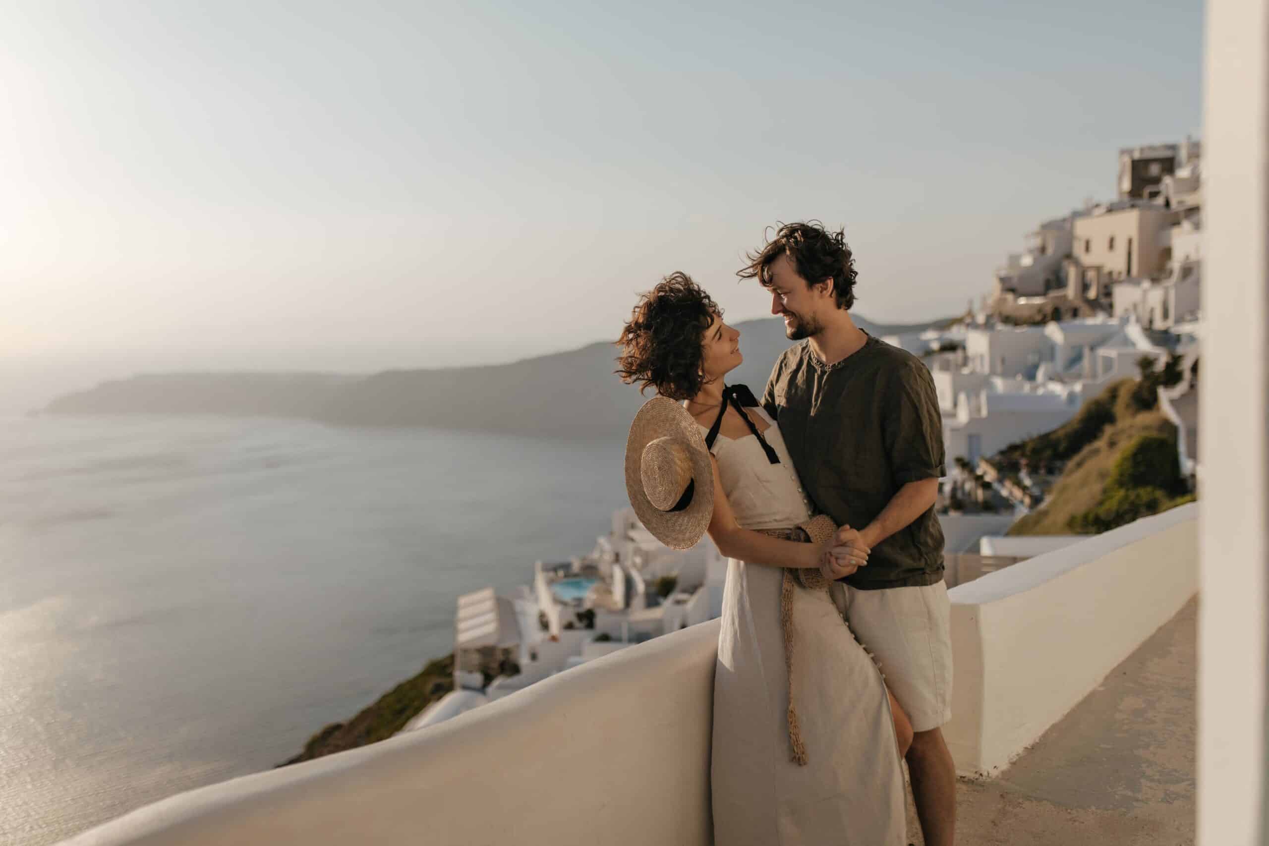 Par nyder en romantisk stund i Santorini, Grækenland, med hvide bygninger og blå himmel i baggrunden.